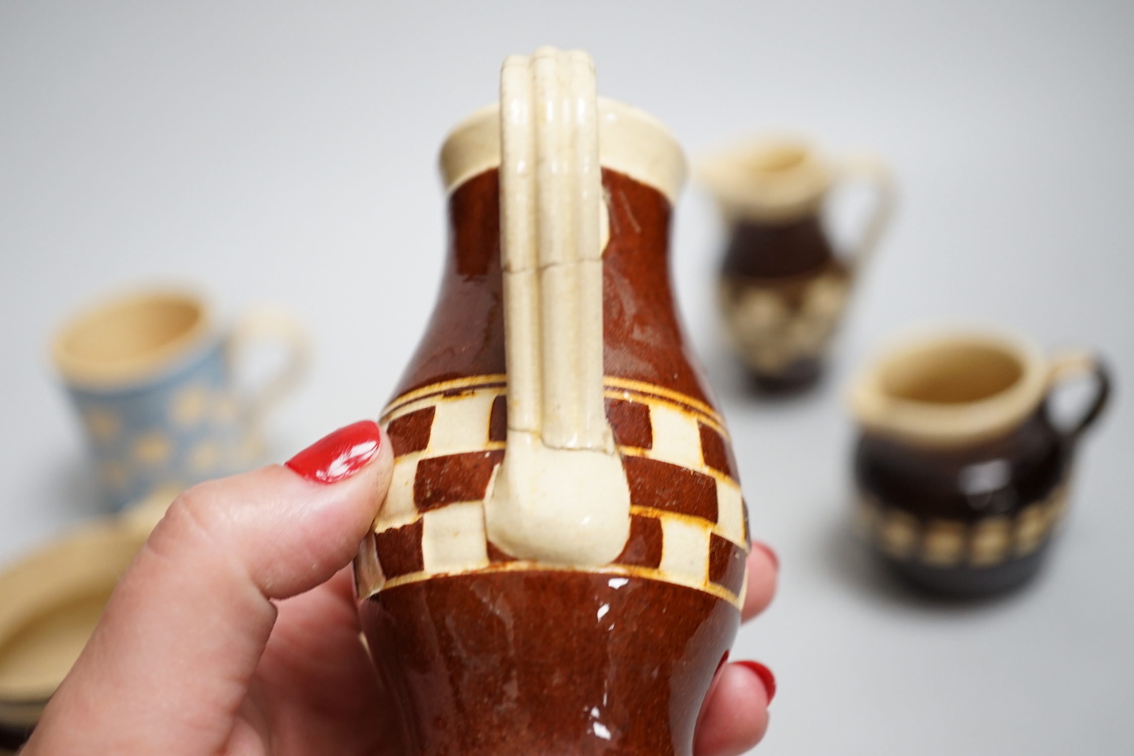 Eight 19th century slip-decorated creamware chequer-pattern jugs and mugs, tallest 10cm